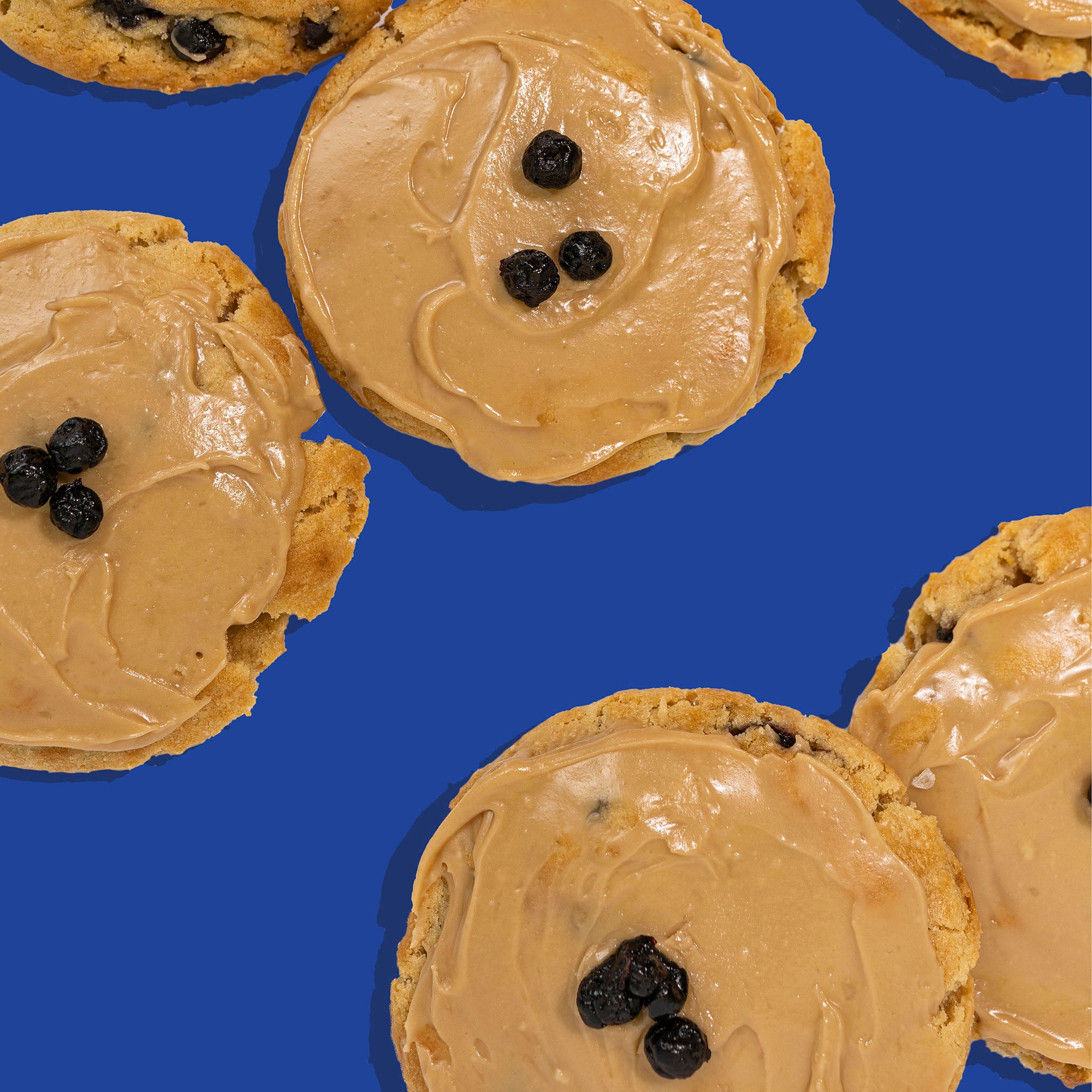 multiple blueberry pancake cookies with maple glaze and blueberry garnish