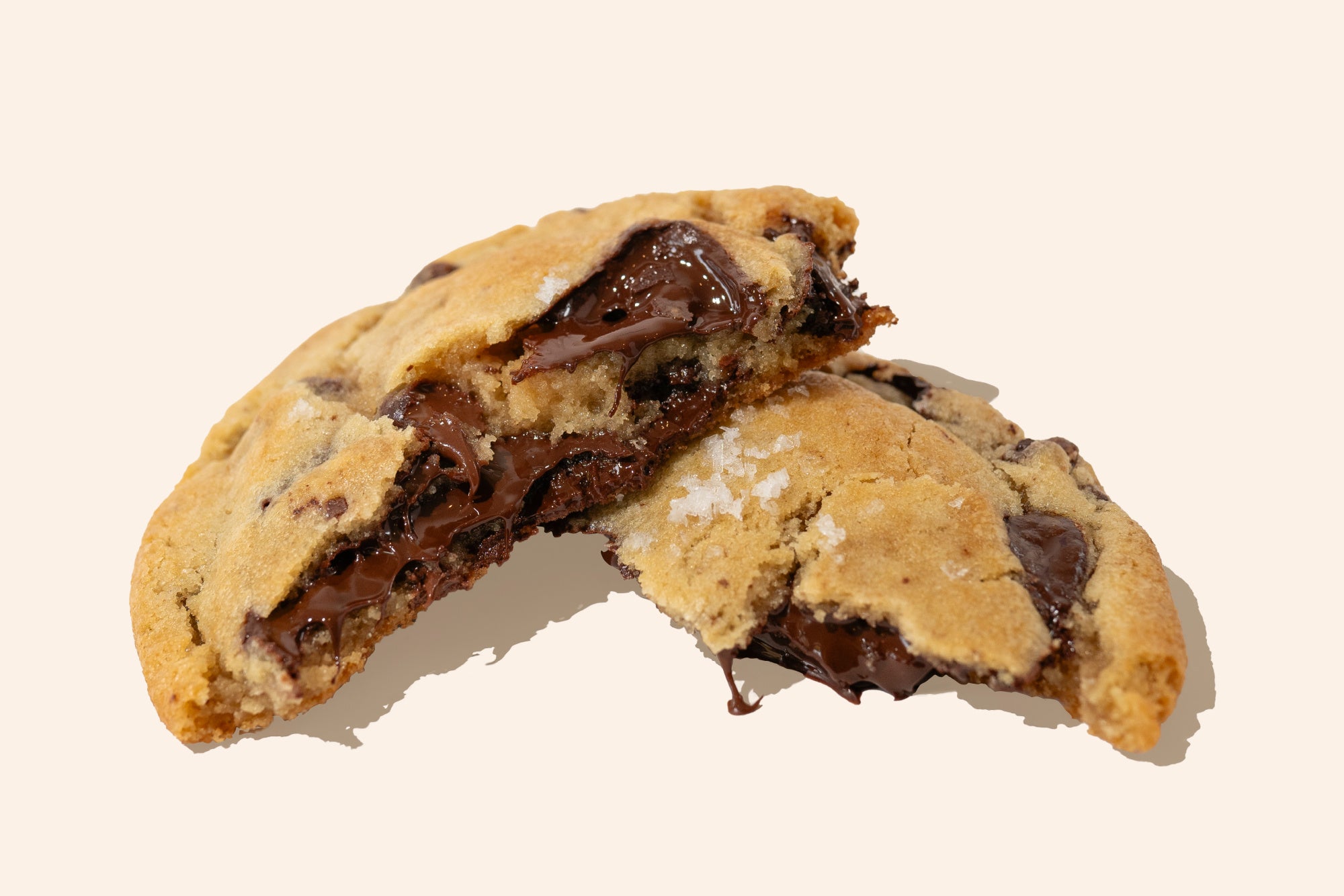 cross section of a gooey chocolate chip cookie broken in half, topped with maldon sea salt