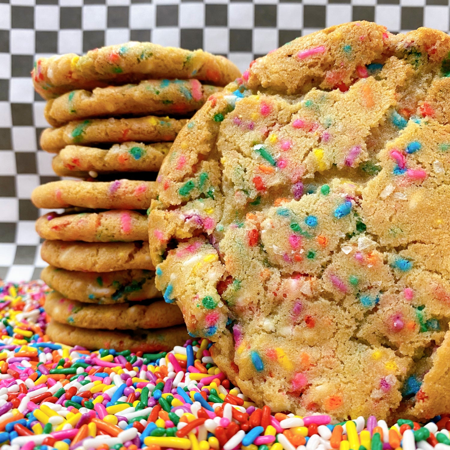 rainbow sprinkle sugar cookie in piles of rainbow sprinkles with checkered background