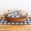 basket full  of wrapped and stickered cookies sitting on a wood table with a checkered runner